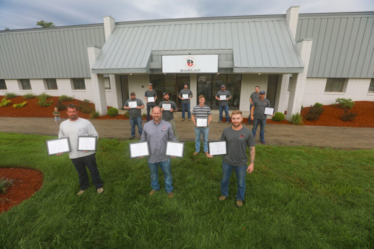 Harlan employees outside office building holding awards