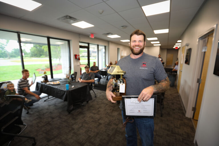 Harlan employee holding two awards at office
